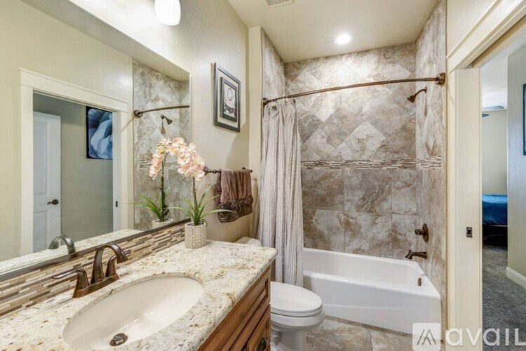 A bathroom with a marble wall and a white bathtub.