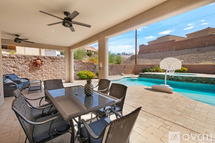 A patio with a table and chairs and a pool in the background.