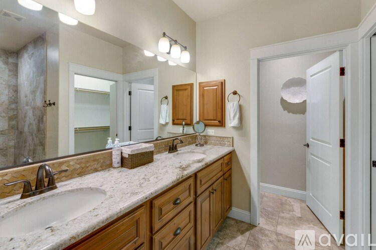A bathroom with a marble countertop and wooden cabinets.