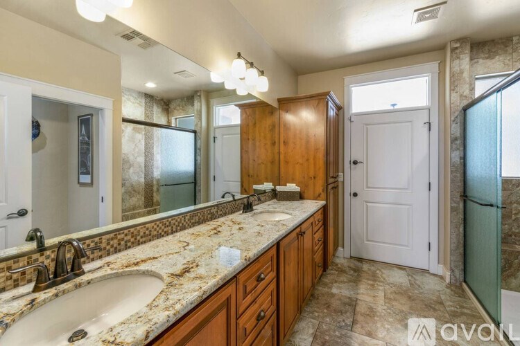 A bathroom with a marble countertop and a large mirror.