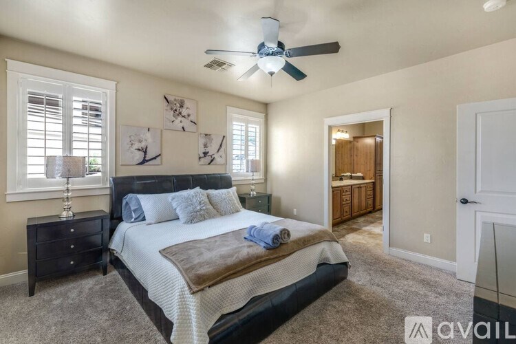 A bedroom with a large bed and a ceiling fan.