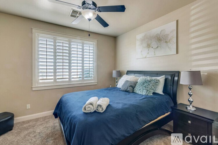 A bedroom with a bed, a ceiling fan, and a window with blinds.