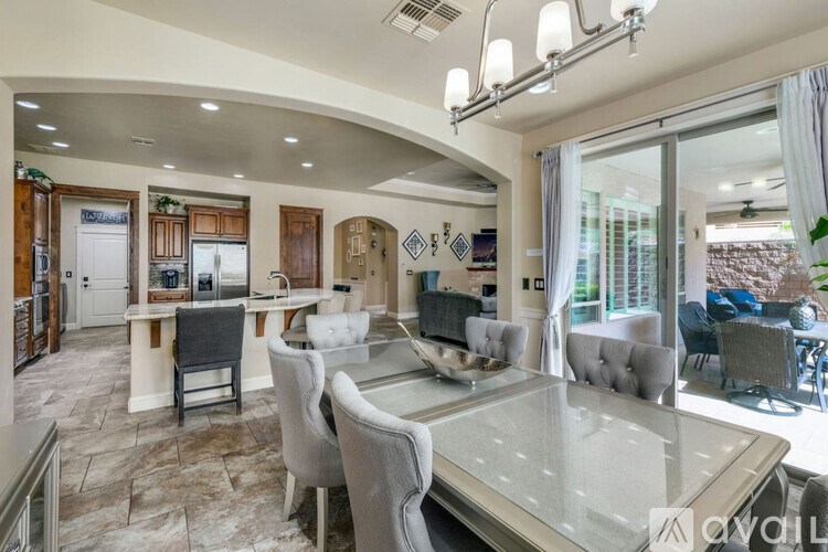 A modern dining room with a glass table and grey chairs.