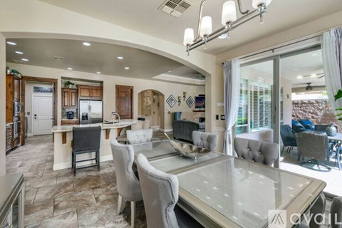 A modern dining room with a glass table and grey chairs.