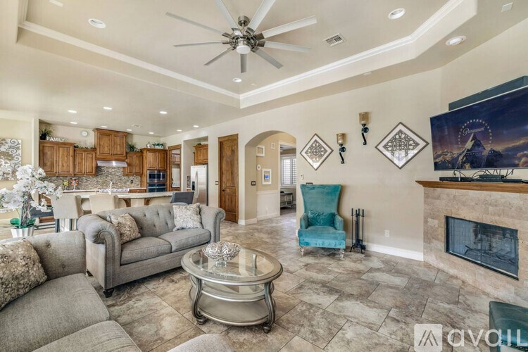 A living room with a grey couch, a blue chair, and a fireplace.