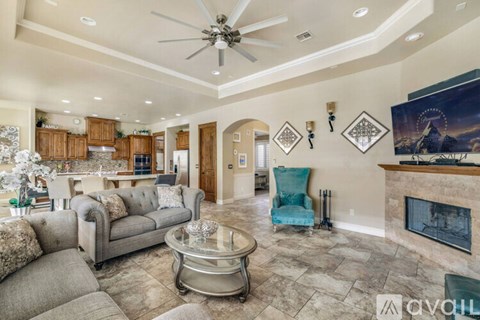 A living room with a grey couch, a blue chair, and a fireplace.