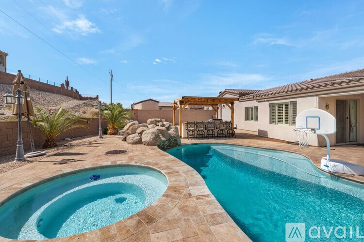 A pool with a basketball hoop in the backyard of a house.