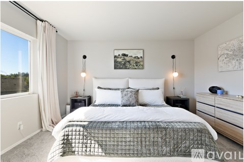 A bedroom with a large bed, two lamps, and a painting on the wall.