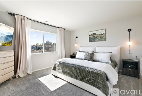 A bedroom with a large bed, a window with curtains, and a picture on the wall.