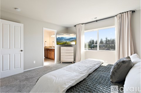 A bedroom with a large bed and a view of the outdoors through the window.
