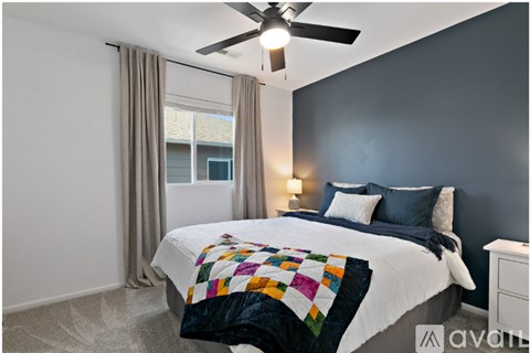A bedroom with a bed, a ceiling fan, and a window with curtains.