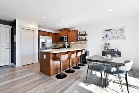 A modern kitchen with a bar stool and a dining table.