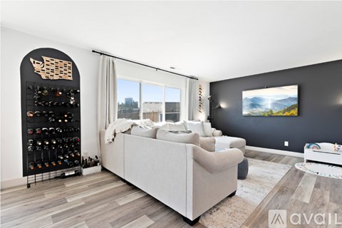 A living room with a large couch and a wine rack.
