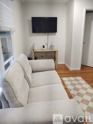 A living room with a white couch and a television mounted on the wall.