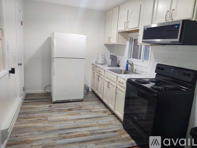 A kitchen with a black stove top oven and a white refrigerator.