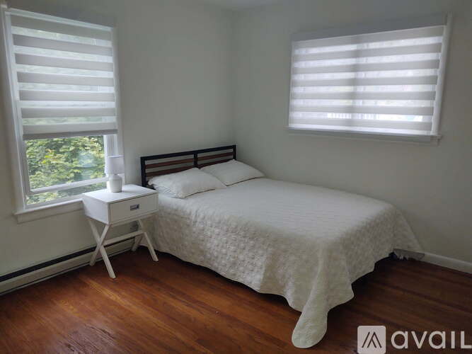 A bedroom with a bed, nightstand, and window with blinds.