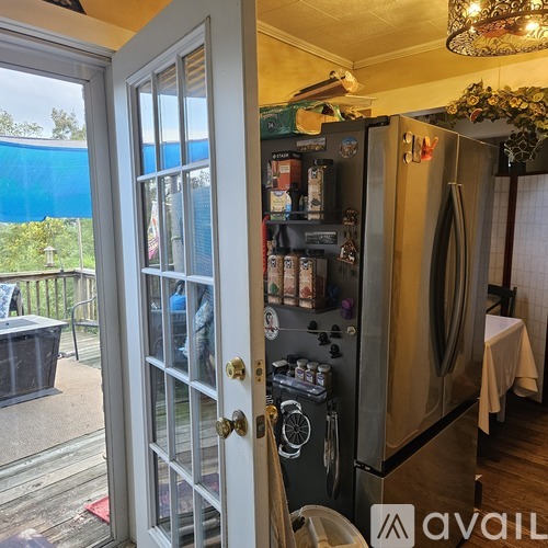 A kitchen with a refrigerator and a door open to a balcony.