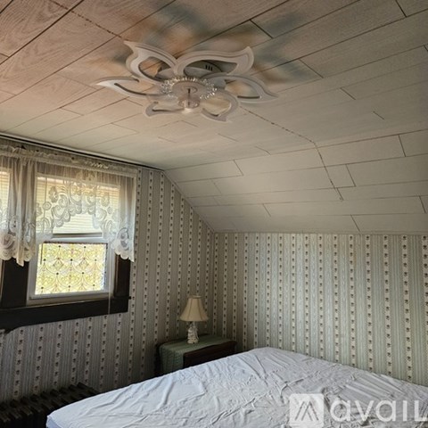A bedroom with a bed, a ceiling fan, and a window with curtains.