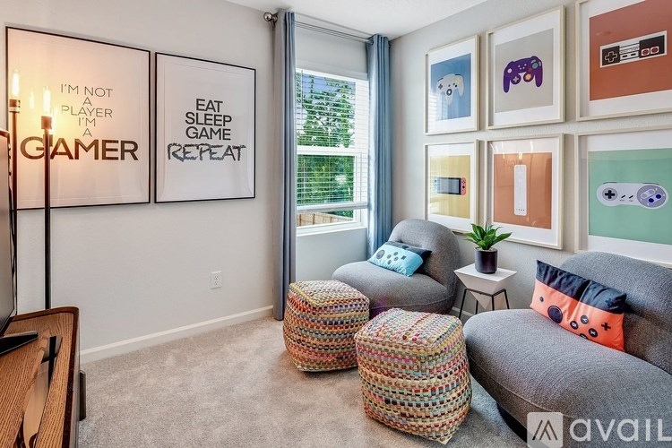 A living room with a couch, ottoman, and a wall with framed art and a sign that says "I'm not a gamer, I'm a player.".