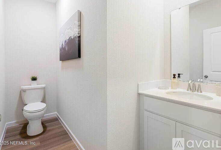 A bathroom with a toilet, sink, and mirror.