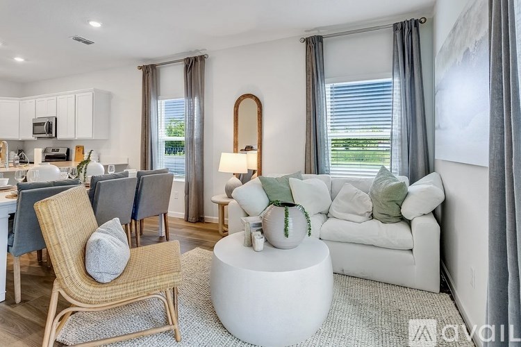 A living room with a white couch, a wooden chair, and a round white table.