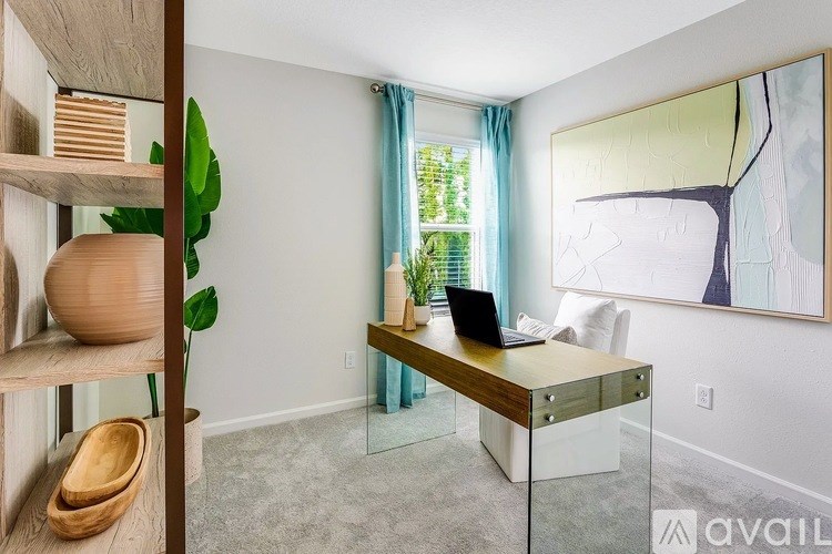 A room with a desk, chair, and a plant.