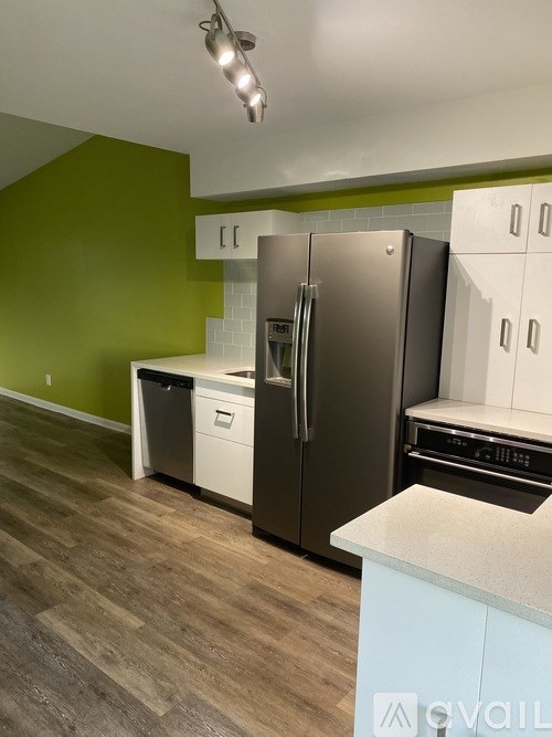 A kitchen with a green wall and a stainless steel refrigerator.
