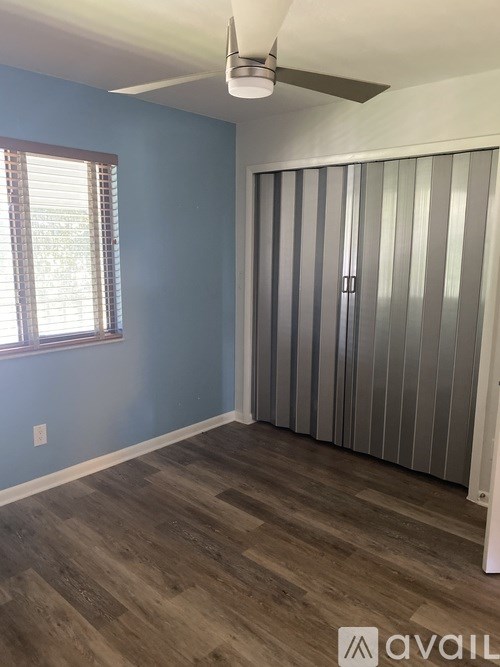 A room with a ceiling fan and a window with blinds.