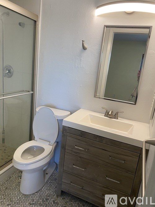 A bathroom with a toilet, sink, and mirror.
