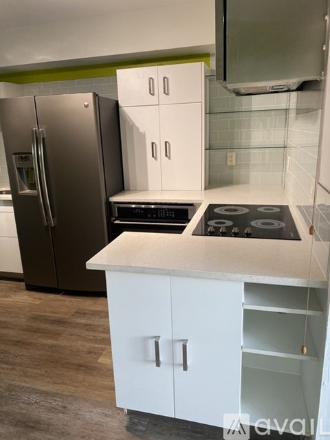 A kitchen with a white counter and a stainless steel refrigerator.
