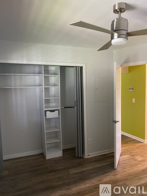 A room with a ceiling fan and a yellow door.