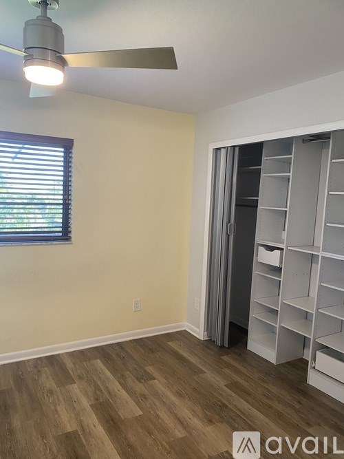 A room with a ceiling fan and a window with blinds.