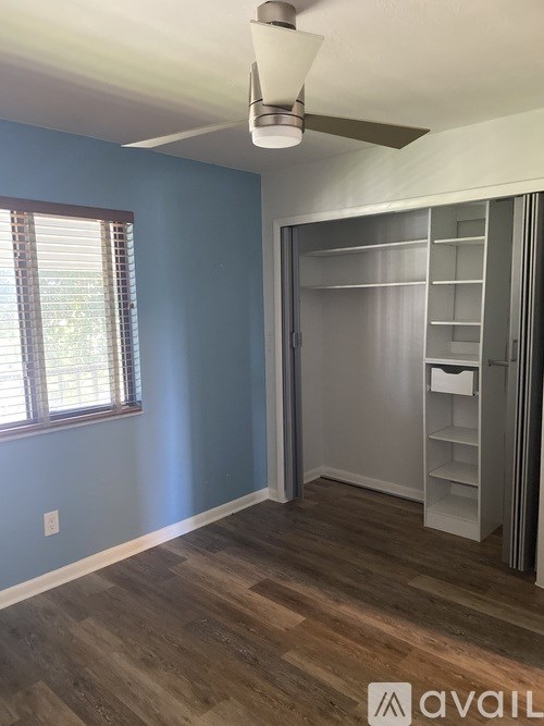 A room with a ceiling fan and a wooden floor.
