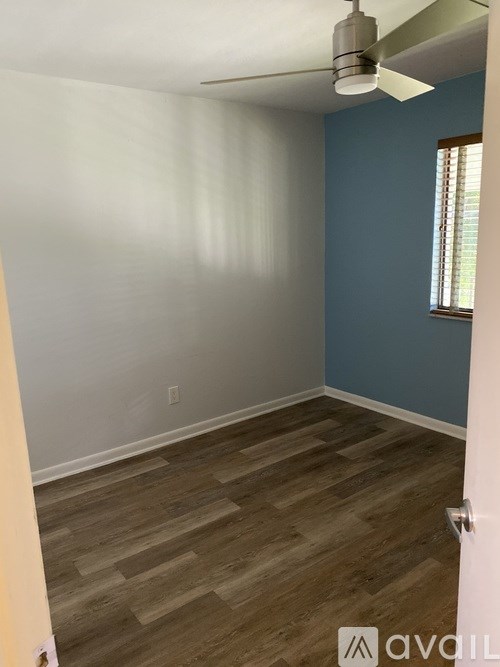 A room with wooden flooring and a ceiling fan.