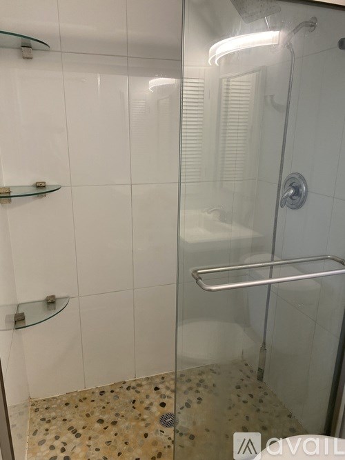 A shower with a glass door and a glass shelf above it.
