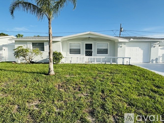 A white house with a palm tree in front of it.