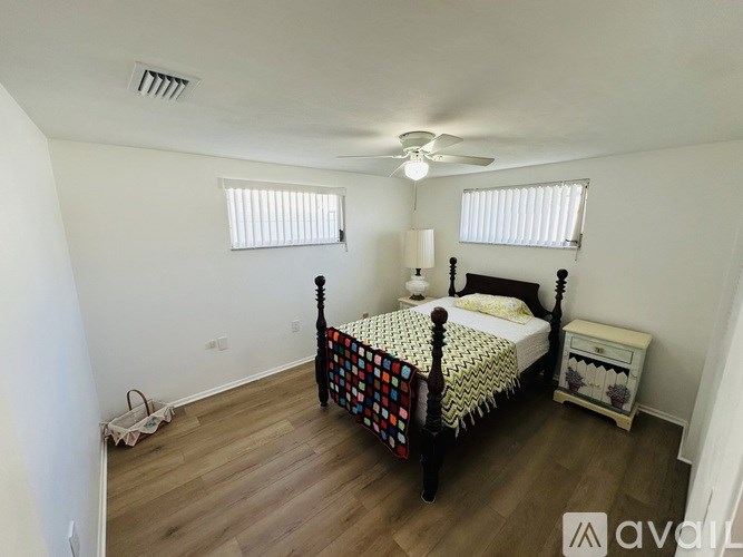 A bedroom with a bed, nightstand, and window blinds.