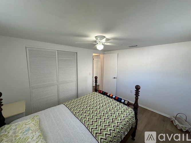 A bedroom with a bed, a chair, and a window with blinds.