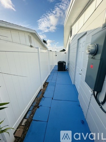 A narrow alley with a blue tiled floor and white walls.