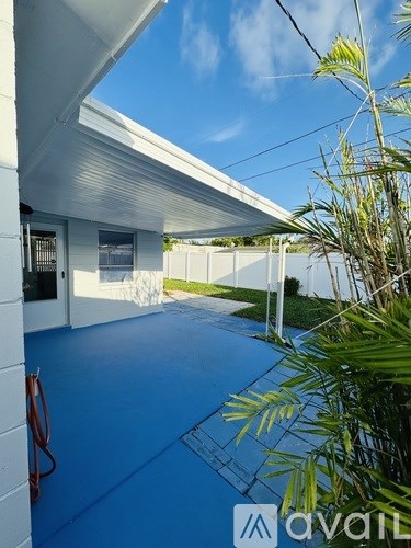A white building with a blue floor and a red hose.