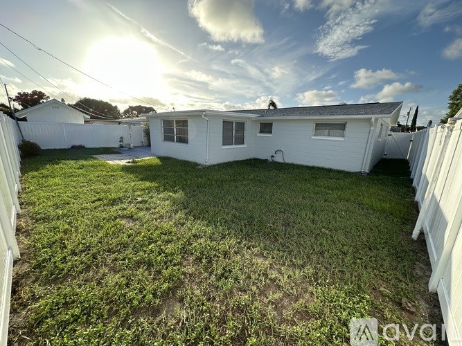 A backyard with a white fence and a house in the background.