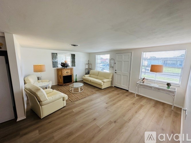 A living room with white furniture and a wooden floor.