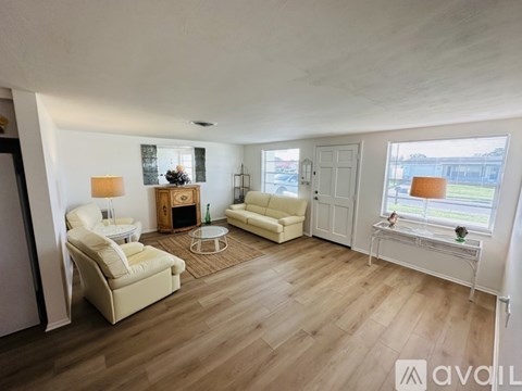 A living room with white furniture and a wooden floor.