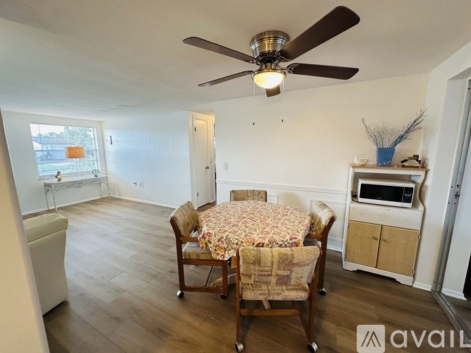 A dining room with a table set for four and a ceiling fan.