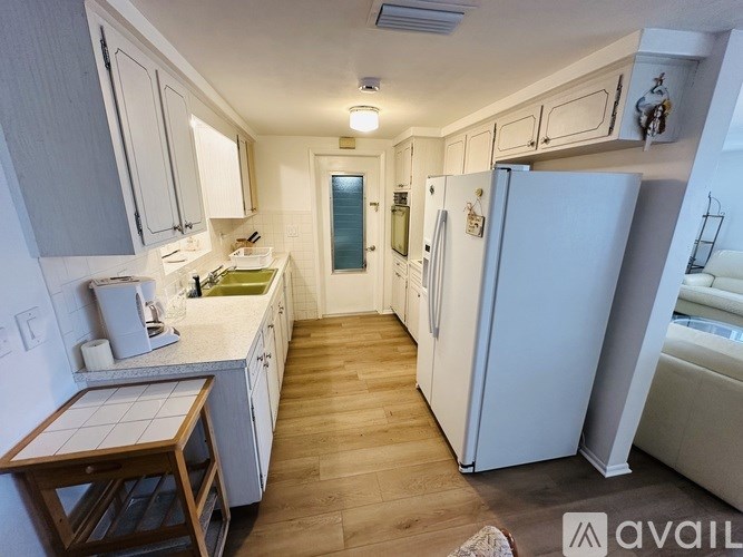 A kitchen with white appliances and wooden floors.