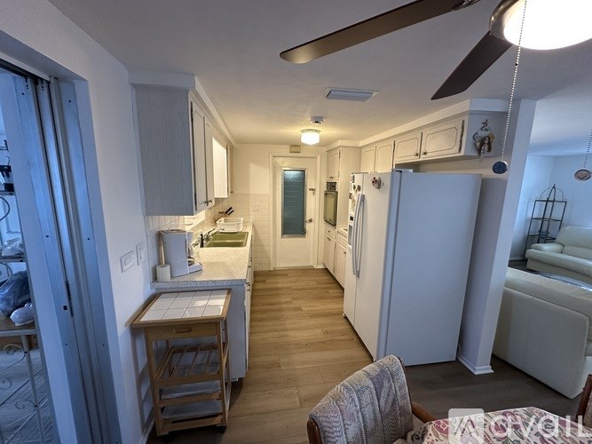 A kitchen with white appliances and wooden floors.