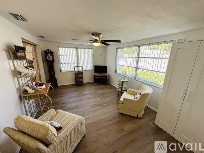 A living room with a couch, chair, and a fan.