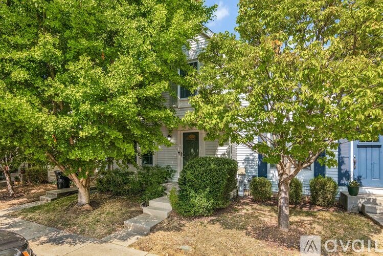A white house with a blue door and a tree in front.