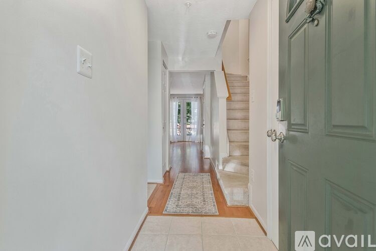 A hallway with a rug on the floor and a door on the right.