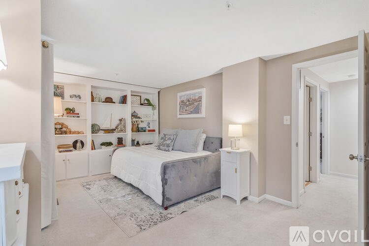 A bedroom with a bed, nightstand, and shelves with various items.
